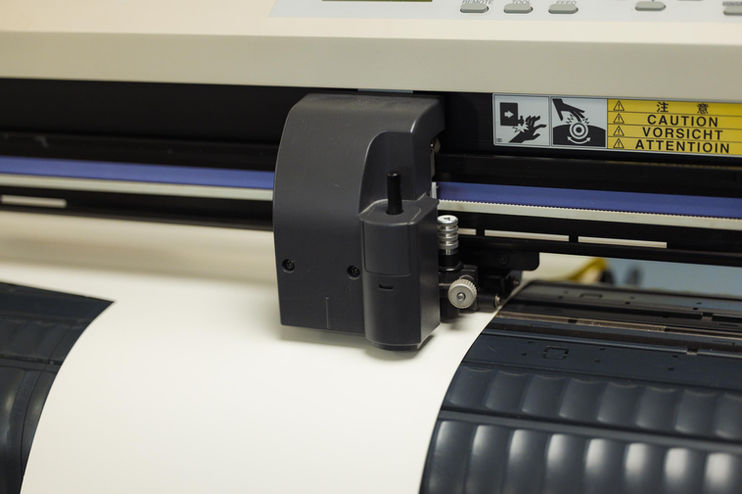 Nahaufnahme Schneideplotterkopf mit weißem Material, Text CAUTION VORSICHT.