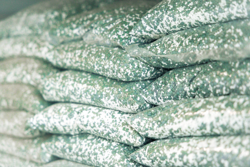 Mehrere Tüten liegen auf einer Palette. Sie sind mit grün-weißen Kunsstoffpellets gefüllt.