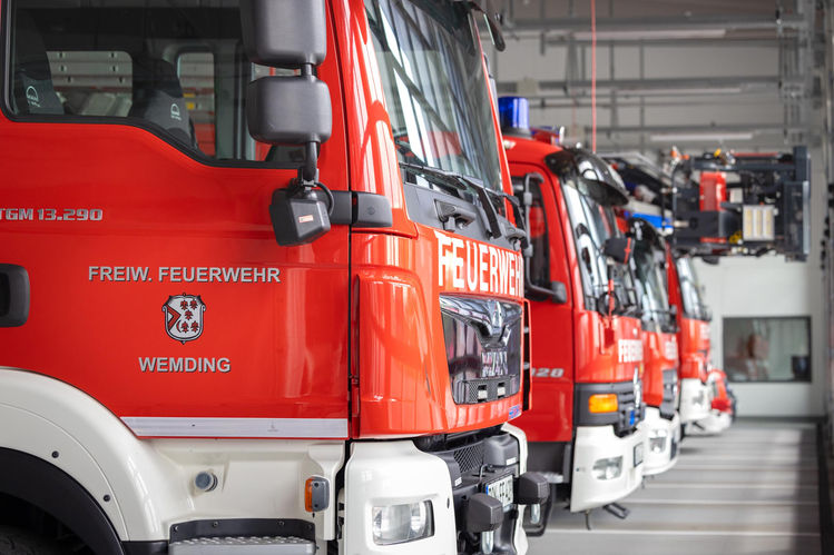 Garage einer Feuerwehrstation. Drei Feuerwehrautos stehen darin.