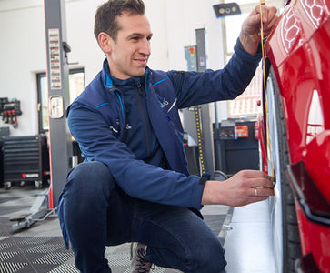 Markus Beutmiller misst eine Felge eines roten Autos aus.