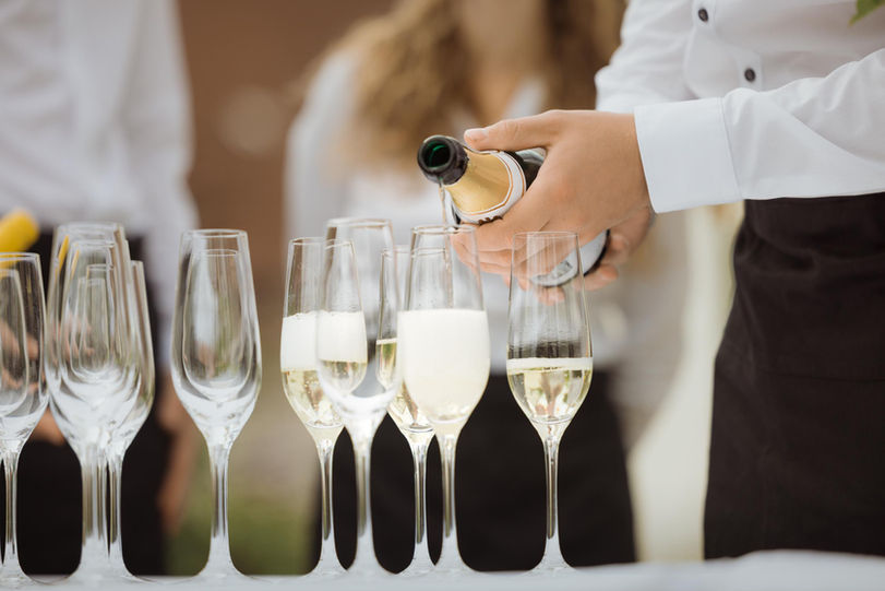 Kellner gießt Champagner in Gläser; weitere Gäste im Hintergrund. Gut Sulz.