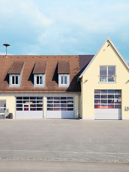 Die Feuerwehrwache in Berg. Drei Rolltore sind zu sehen. Dahinter stehen die Feuerwehrfahrzeuge.