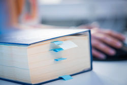 Nahaufnahme eines Buchs mit vielen Merkzetteln darin.