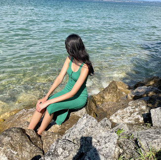 Photograph of Punjabi model Acela ' Ace ' Kandola wearing long green dress sitting on rocks looking back at the ocean