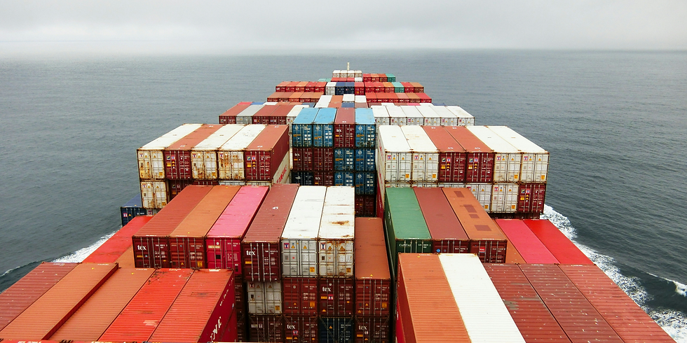 Cargo ship with stacked containers sails through ocean under a cloudy sky.