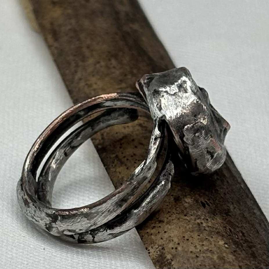 Ancient artifact-inspired ring made from soft-solder on copper wire, size 7, shown from side angle.