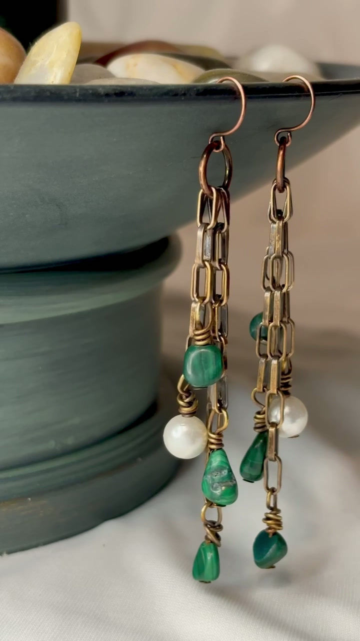 Thumbnail: Boho dangle earrings featuring malachite beads, pearls, and copper chain displayed on a ceramic vase