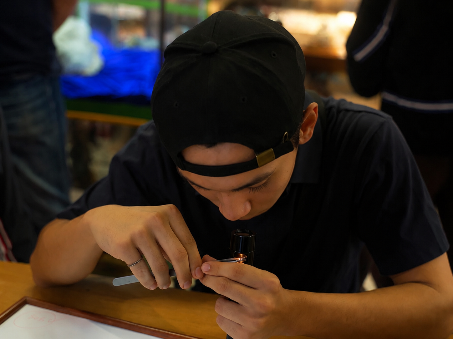19-year-old Viktor in Chantaburi inspecting a gemstone using the same darkfield loupe his father used 29 years earlier. Winter - 2022.