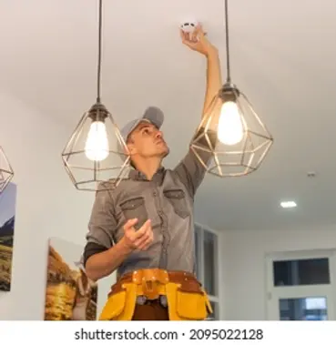 handyman-installing-smoke-detector-on-260nw-2095022128.webp