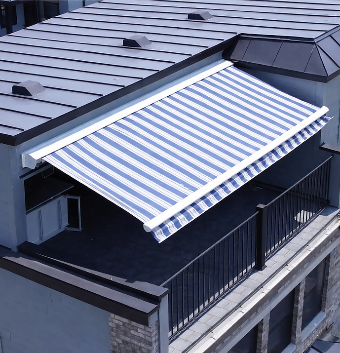 Blue-and-white striped Aristocrat retractable awning with a white frame and scalloped valance shading a modern rooftop penthouse terrace, viewed from above beside a standing-seam metal roof and black railings.