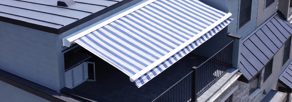 Blue and white striped retractable awning mounted under a under a metal roof in a townhome community in Lodi, NJ Bergen County