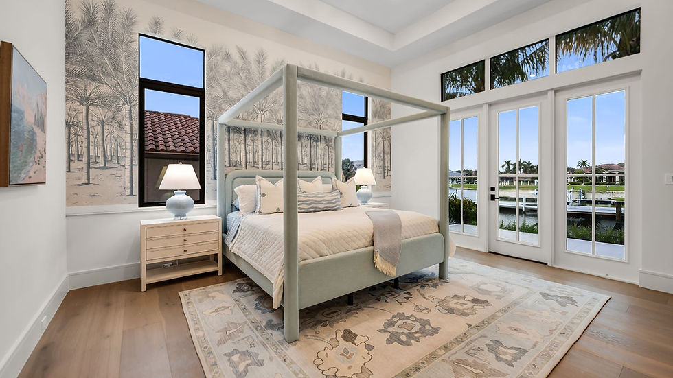 Bright bedroom with pale blue canopy bed, palm tree mural, patterned rug, and glass doors opening to a sunny waterfront view