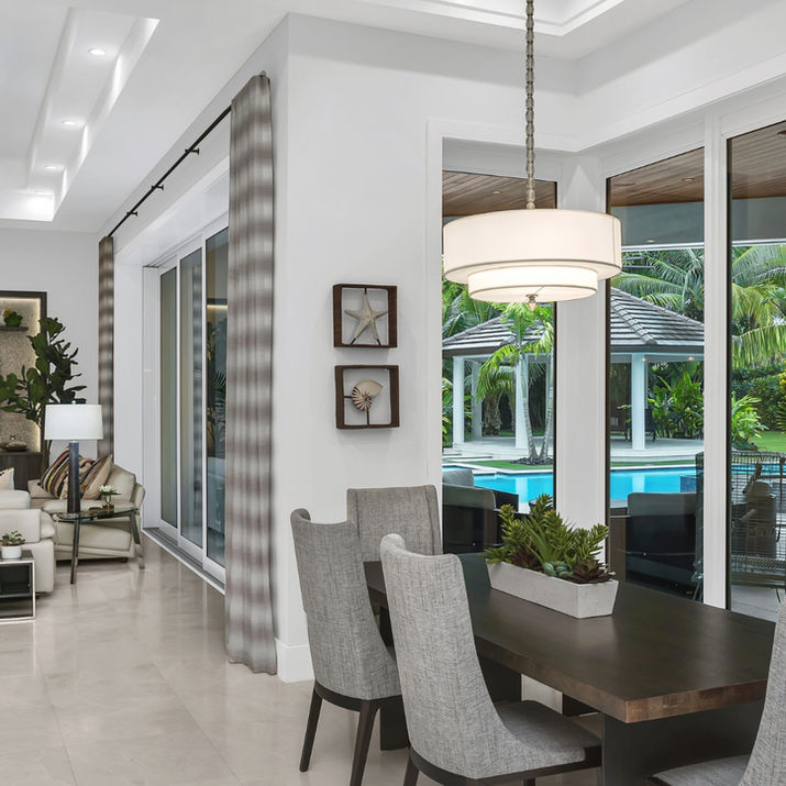 Open-concept great room and dining area with pool views through expansive floor-to-ceiling windows.