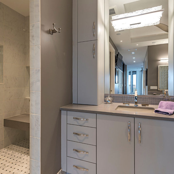 Primary bathroom with gray vanity, walk-in shower, marble tile, and large mirror.