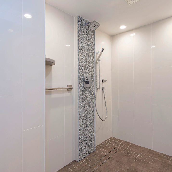 Walk-in shower with bench, handheld fixture, mosaic accent tile, and glossy wall panels.