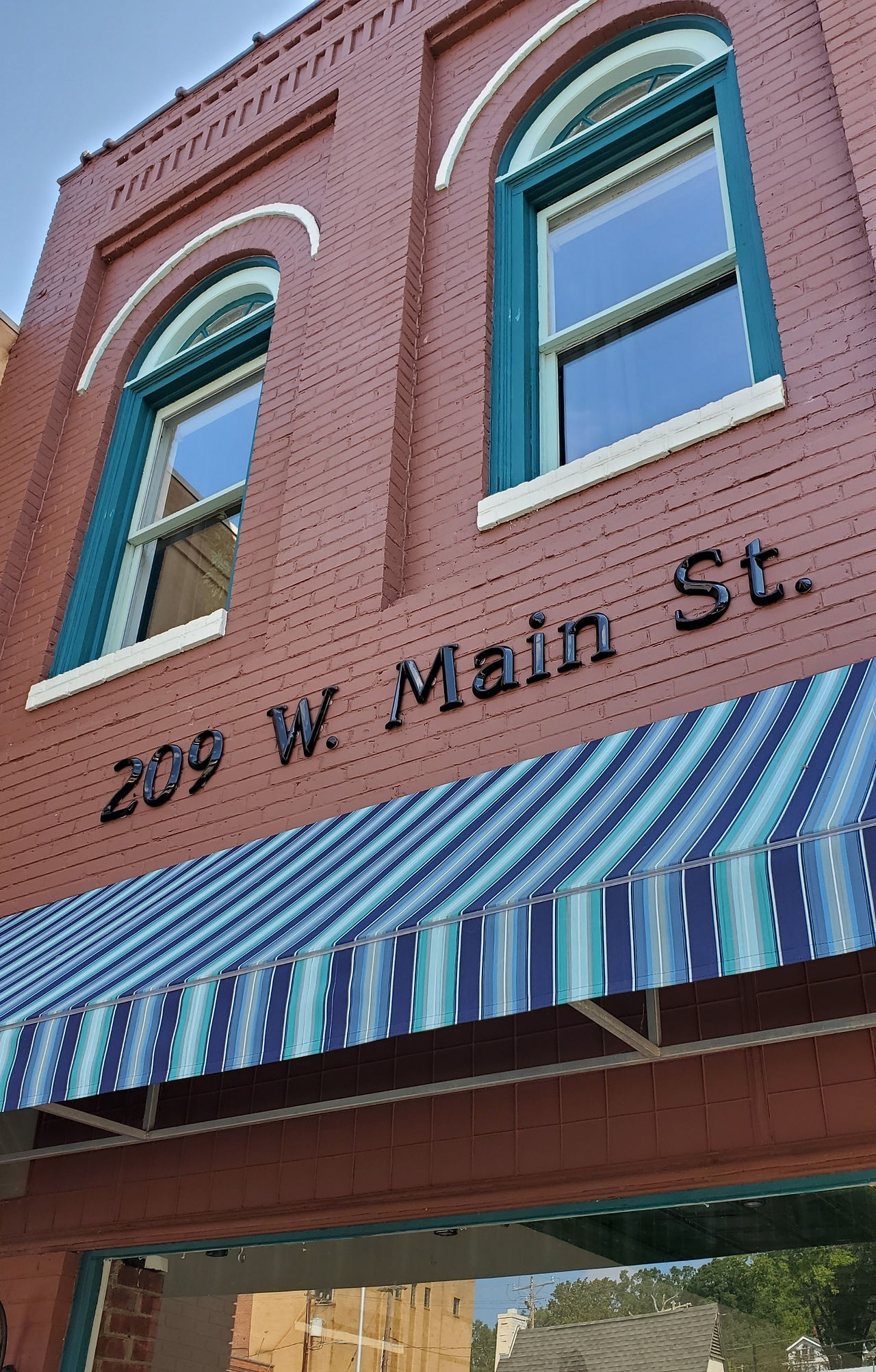 Red brick building displays "209 W. Main St." above a striped awning.