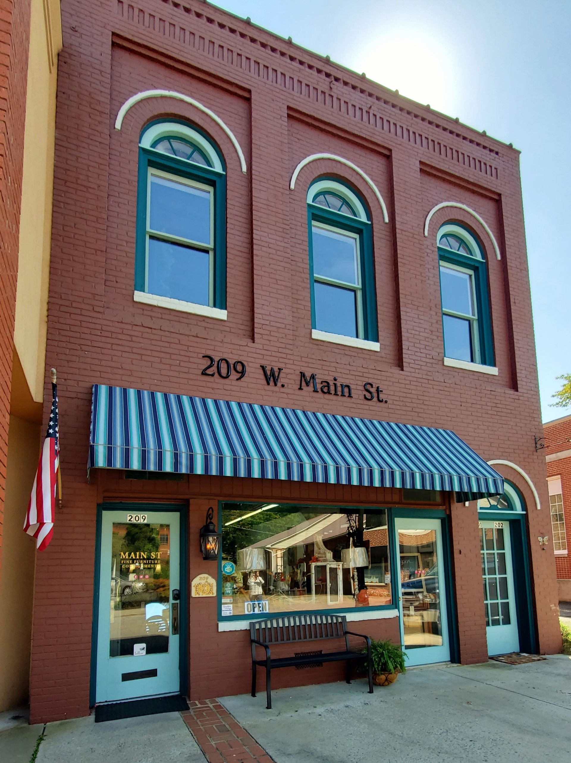 Brick building with striped awning, 209 W. Main St. storefront.