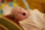 A young baby yawns with closed eyes.