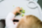 A baby's hand grabs pieces of broccoli