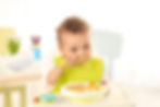 A baby feeds himself with a spoon