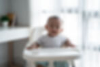 A baby sits upright in a high chair