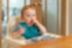 A baby puts a piece of finger food in his mouth