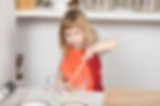 A young girl mixes with a wooden spoon