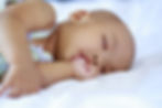 A sleeping baby sucking on their thumb