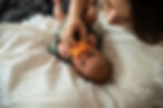 A mother holds a pacifier in a young baby's mouth.