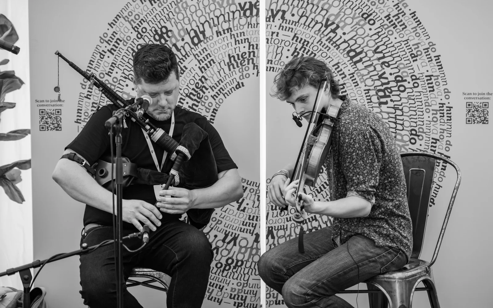 Donald and Roo playing smallpipes and fiddle together, photographed in black and white at Piping Live