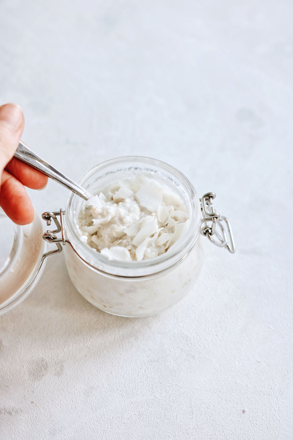 A hand takes a spoonful of dairy free coconut milk oatmeal.