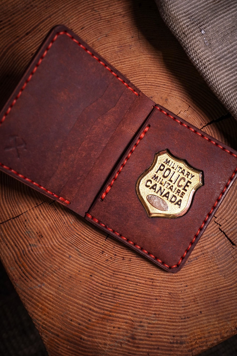 Open brown and red stitched wallet holding a Canadian Forces Military Police badge
