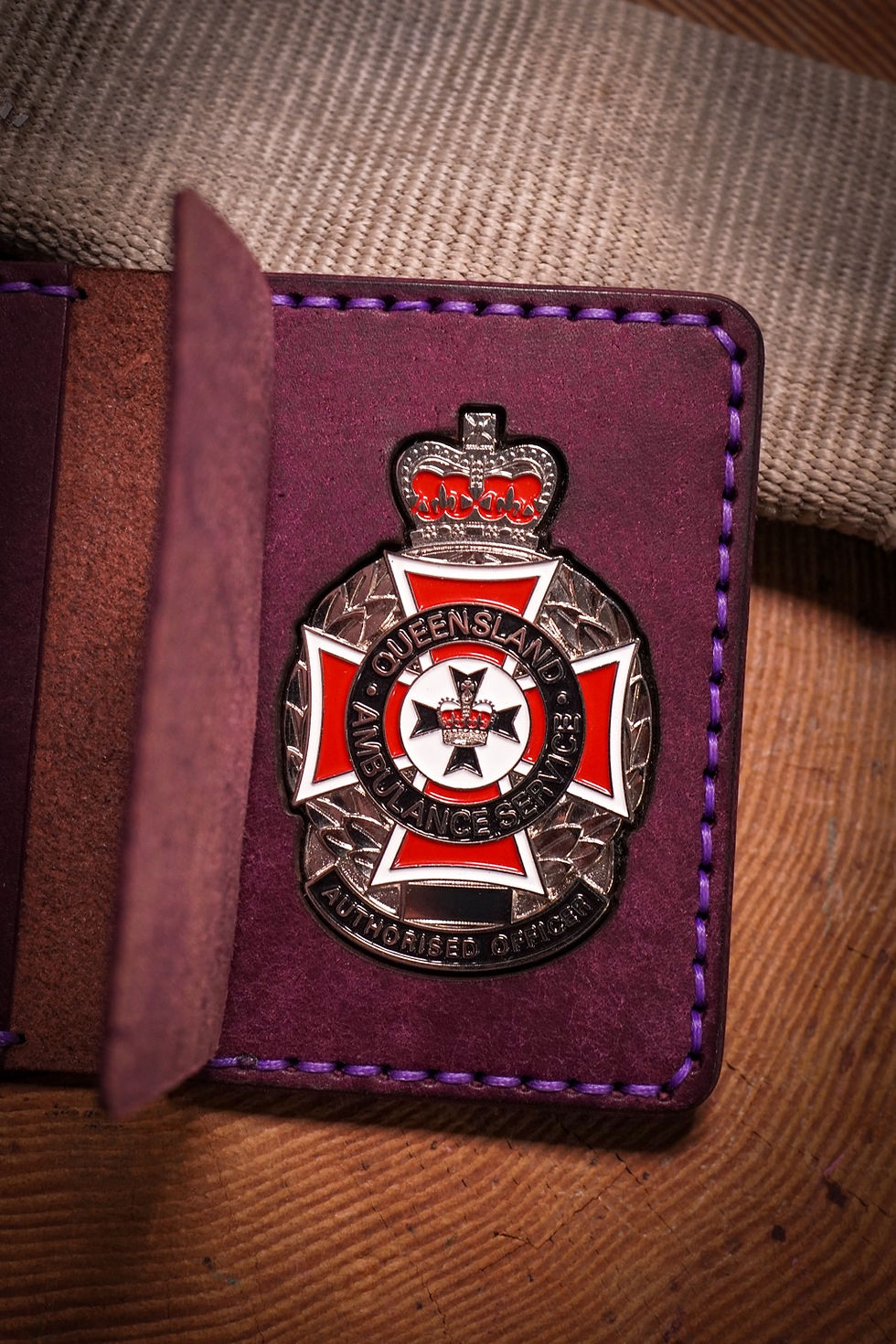 Purple leather wallet with a Queensland Ambulance Service authorised officer badge