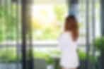 rear-view-woman-standing-by-window-home.jpg