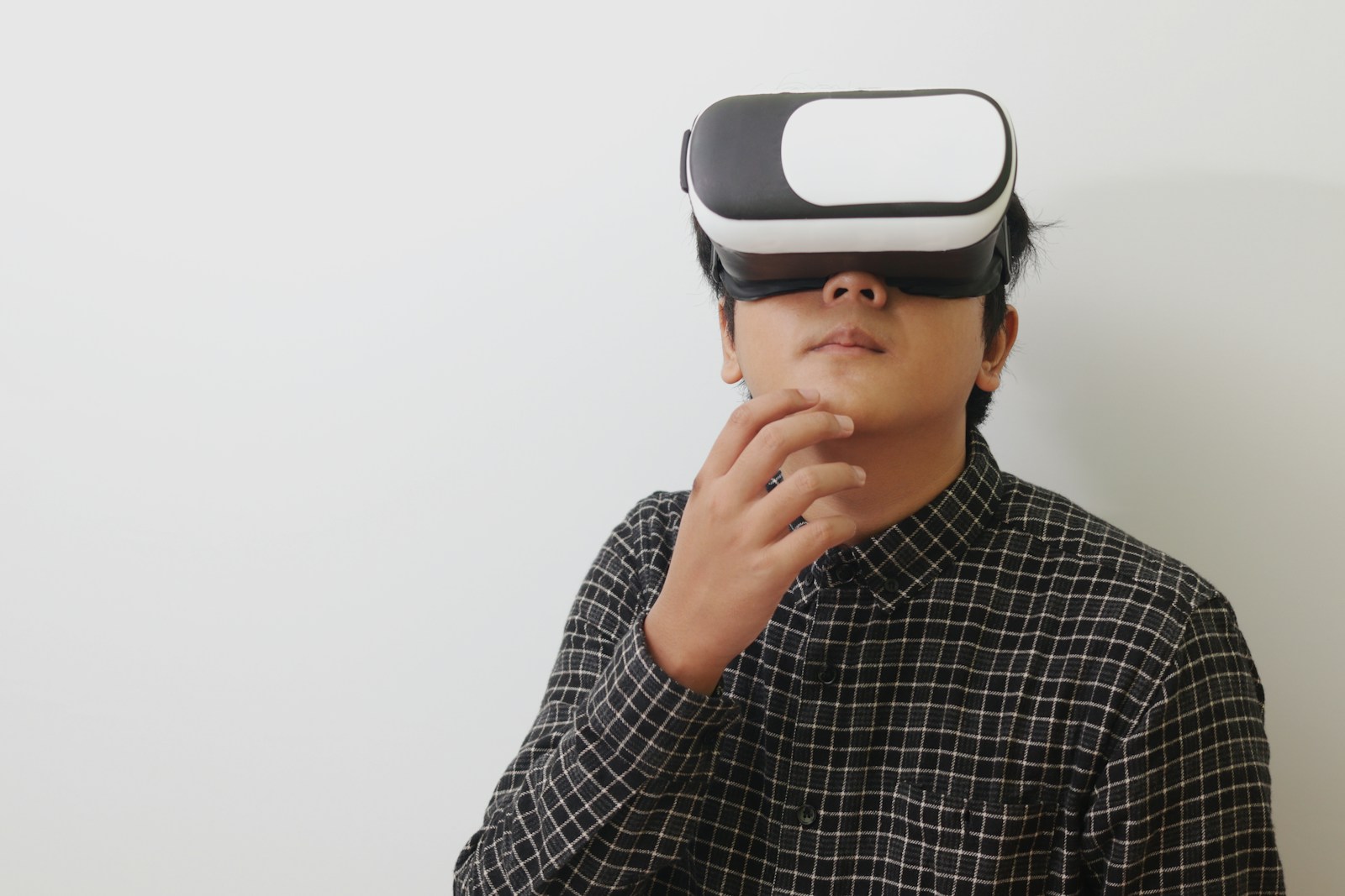 Person wearing a virtual reality headset against a light wall
