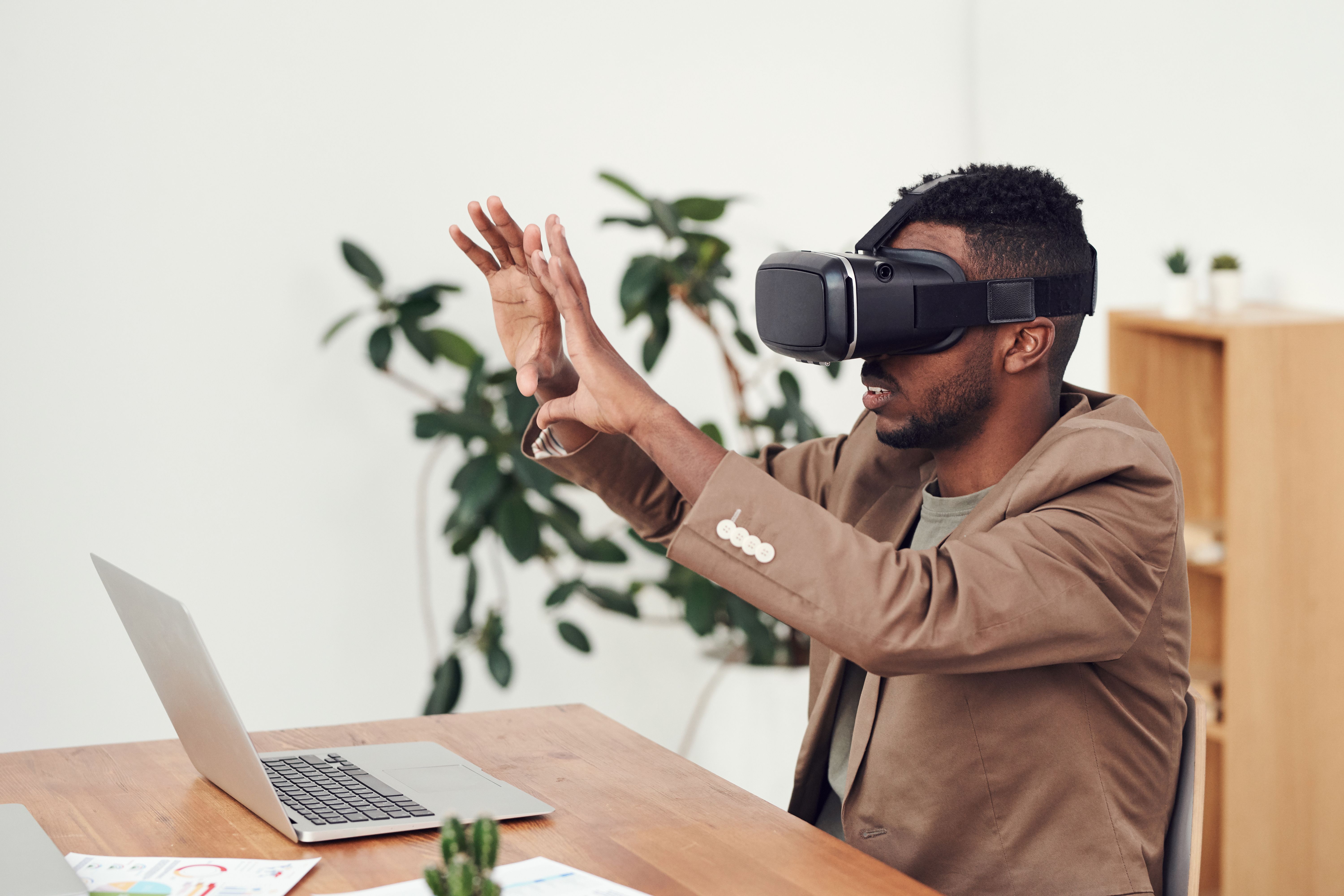Office professional using a virtual reality headset beside a laptop