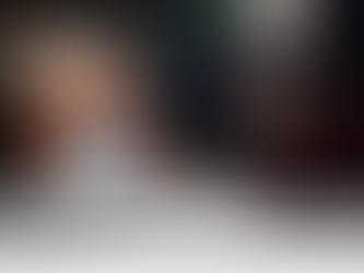 User gestures to a laptop displaying a smiling animated avatar. Text: Industries Using Conversational AI. Room setting, warm lighting.onal AI Avatars