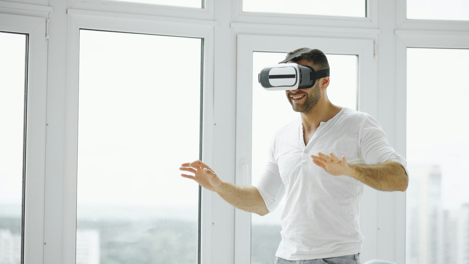 Person wearing a VR headset with hands raised in a bright room