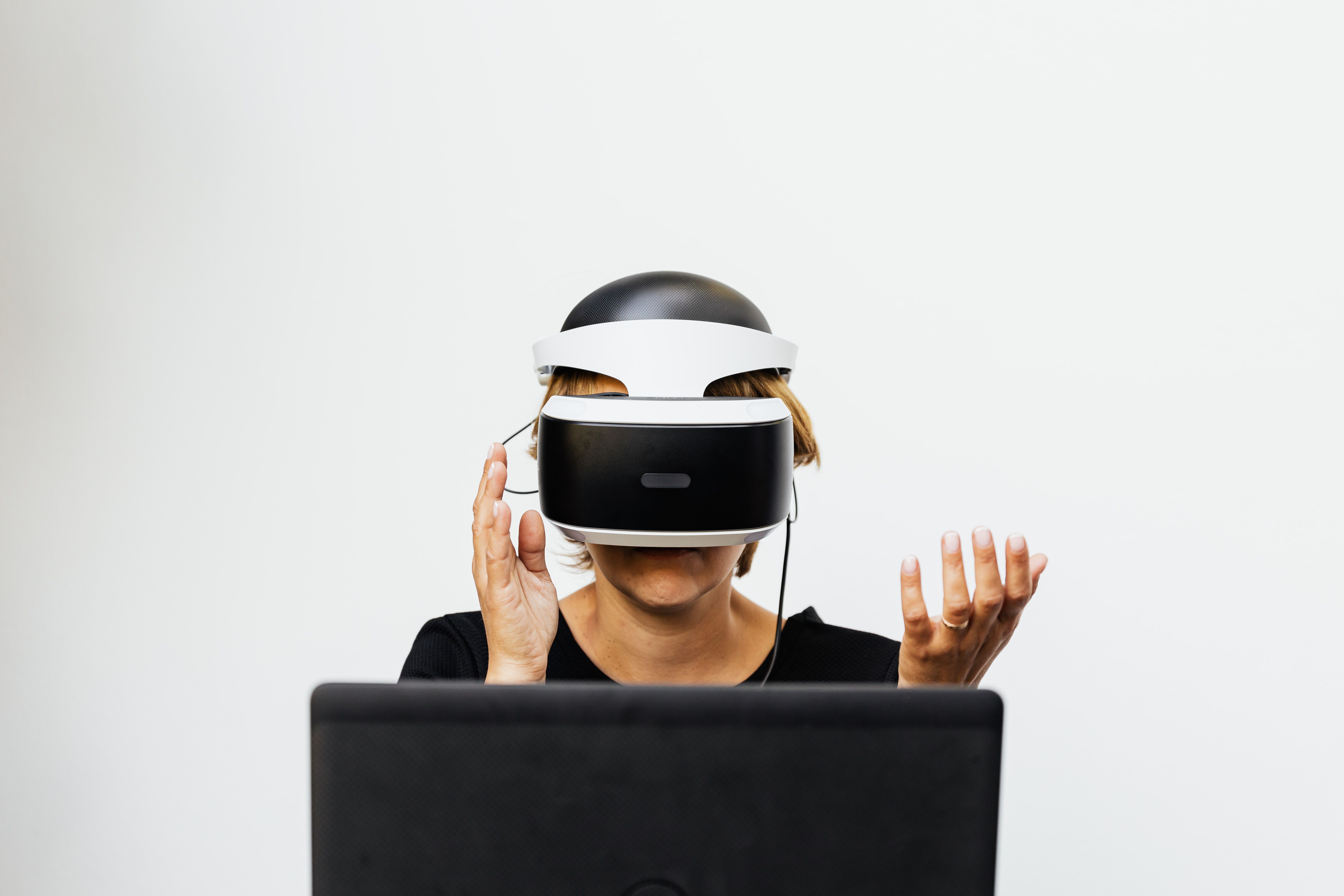 Woman wearing a headset and interacting with a virtual environment at a computer