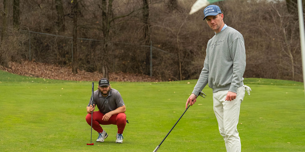 Two golfers reading a putt on the green