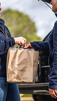 ONe women handing a shopping bag over to another women