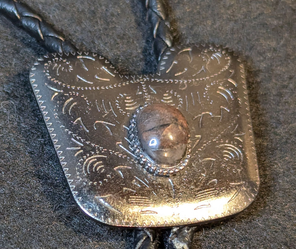 Finished bolo tie featuring a cabochon cut from the uraninite slab set in an industrial style metal mounting
