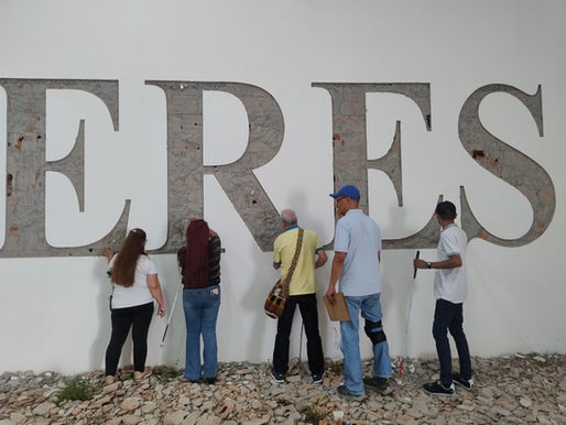 Grupo de personas con discapacidad visual tocando la obra de arte Polvo eres