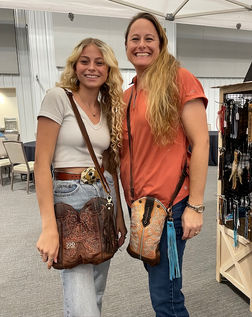 Two women with purses pose for a photo at a store.