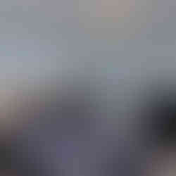 A second bedroom has light blue walls, tan carpeting, a long high window and white trim. There is a large bed, a large dresser with mirror and a nightstand.