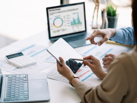 Person analysiert Daten und Diagramme auf Laptop und Tablet im Büro, arbeitet mit KI-gestützten Auswertungen im Arbeitsalltag eines Unternehmens