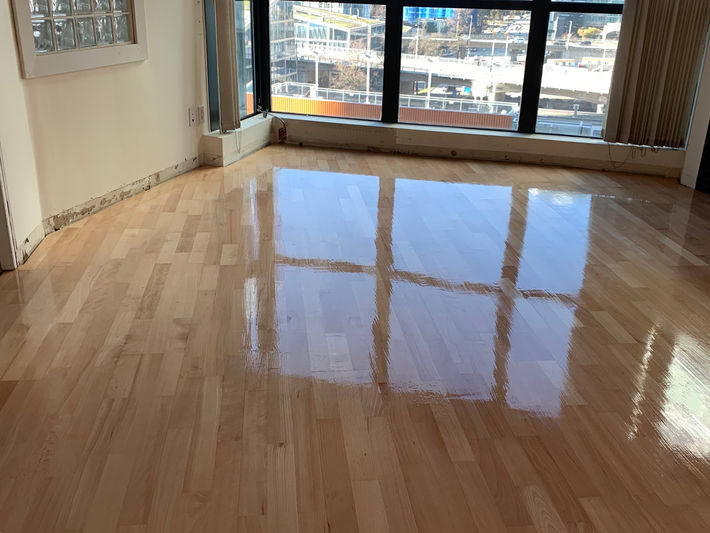 Luxury refinished wide-plank oak hardwood floors in Vancouver high-rise condo – high-gloss light natural finish with panoramic downtown skyline views.
