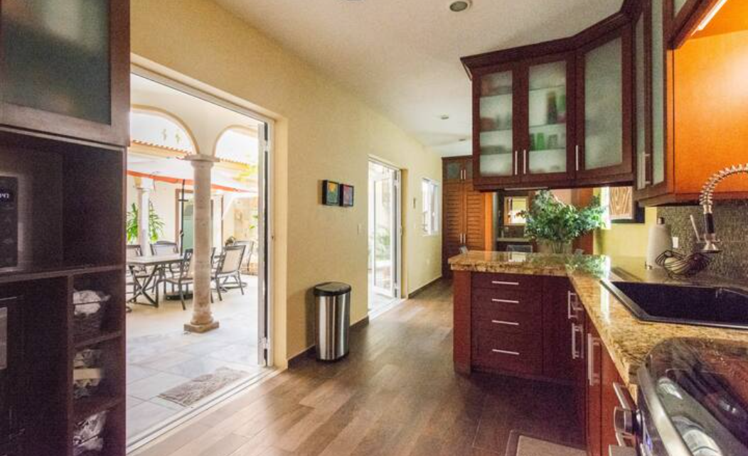 6-burner gas stove, oven, large black granite composite sink, vegetable sprayer, under cabinet lighting, marble countertops, double-door refrigerator with bottom freezer, ice, water dispenser, microwave. French doors open to courtyard.