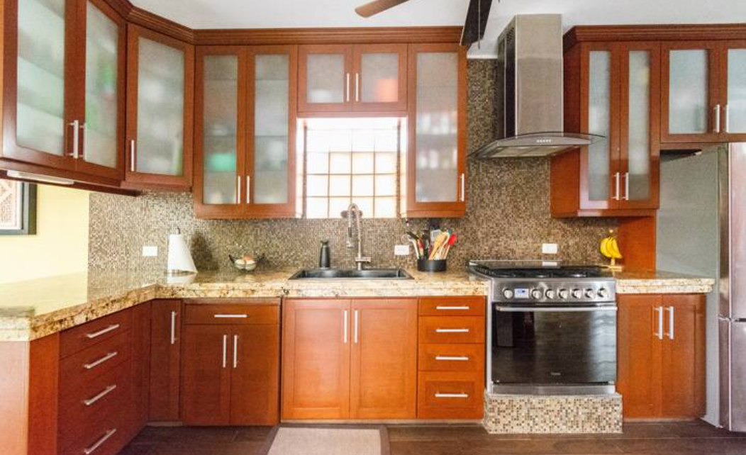 6-burner gas stove, oven, large black granite composite sink, vegetable sprayer, under cabinet lighting, marble countertops, double-door refrigerator with bottom freezer, ice, water dispenser, microwave. French doors open to courtyard.