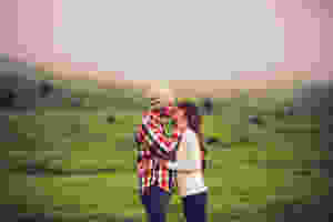 couple kissing, plaid shirt, beany, winter hat, white sweater, white jumper, cute couple, field, countryside, kissing in field, couple stealing a kiss, private moment, ireland, scotland, green pasture,